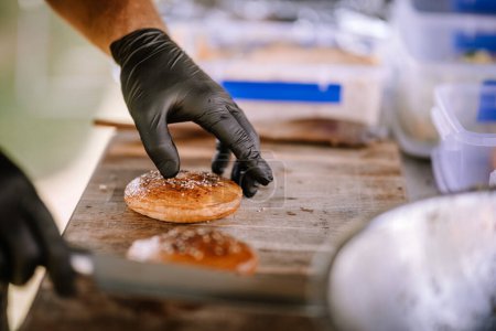 Valmiera, Latvia- July 29, 2023 - A hand in a black glove reaches for a freshly baked bun on a wooden surface.