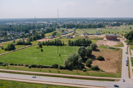 Valmiera, Lettonie - 7 août 2023 - Vue aérienne d'un paysage de banlieue avec maisons, champs verts, routes et arbres.