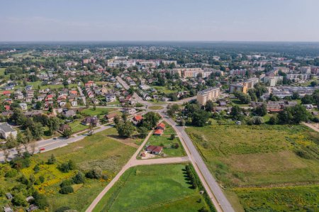 Valmiera, Lettland - 7. August 2023 - Luftaufnahme einer Wohngegend mit Häusern, Gärten, einem Kreisverkehr an einer Hauptstraße und grünen Wiesen, umgeben von Bäumen.