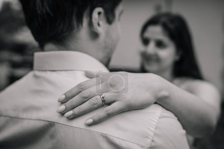 Foto de Mano de mujer con anillo de compromiso en el hombro del hombre, mujer fuera de foco en el fondo. - Imagen libre de derechos