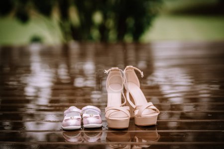 Valmiera, Lettonie - 10 août 2023 - Une paire de talons hauts et de chaussures pour enfants sur un plancher de bois mouillé.