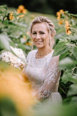 Valmiera, Latvia - August 10, 2023 - Bride smiling amidst sunflowers, holding a bouquet.