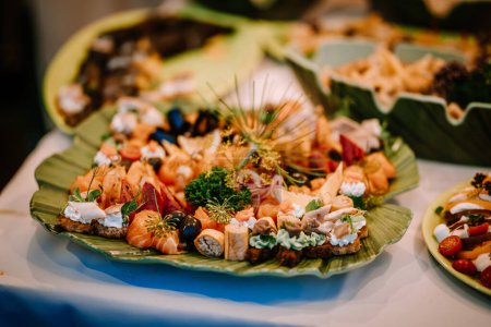 Valmiera, Latvia - August 10, 2023 - Assorted canapes and bites on green leaf-shaped plates at a catered event.