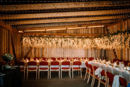 Photo for Valmiera, Latvia - August 10, 2023 - Rustic wedding venue with wooden walls, fairy lights, floral decoration, and set tables. - Royalty Free Image