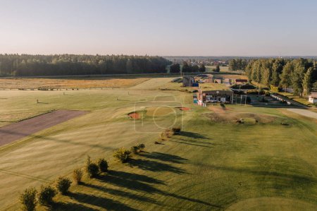 Valmiera, Lettonie - 12 août 2023 - Vue surélevée du terrain de golf au lever du soleil avec club-house et driving range.