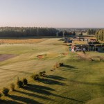 Valmiera, Latvia - August 12, 2023 - Elevated view of golf course at sunrise with clubhouse and driving range.