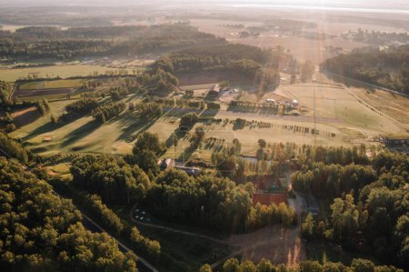 Foto de Valmiera, Letonia - 12 de agosto de 2023 - Vista aérea iluminada por el sol de un campo de golf de 9 hoyos con campo de prácticas y bosque circundante. - Imagen libre de derechos