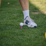 Valmiera, Latvia - August 12, 2023 - Close-up of golfer's legs, golf ball on pink tee, white golf shoes, green grass.