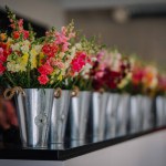 Dobele, Latvia - August 18, 2023 - A row of colorful flowers in metal buckets on a black countertop.