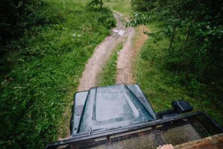 Dobele, Latvia - August 18, 2023 - View from a vehicle driving down a narrow forest road, surrounded by green foliage.