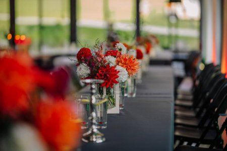 Dobele, Lettonie - 18 août 2023 - Une rangée d'arrangements floraux sur une table pour un événement avec des chaises alignées sur le côté.