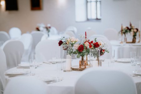 Valmiera, Lettonie - 19 août 2023 - Table de réception de mariage élégamment aménagée avec des pièces maîtresses florales dans un lieu bien éclairé.