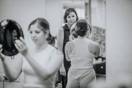 Téléchargez les photos : Valmiera, Lettonie - 19 août 2023 - Une femme regarde sa coiffure dans un miroir à main dans un salon pendant qu'un styliste regarde. - en image libre de droit