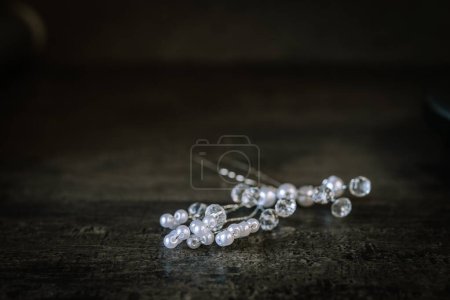 Valmiera, Latvia - August 19, 2023 - Elegant pearl and crystal hairpins on a dark wooden surface.