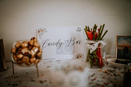 Valmiera, Latvia - August 19, 2023 - A candy bar setup at an event, featuring a sign that reads "Candy Bar", various candies in jars and sticks, and a confetti-strewn table.