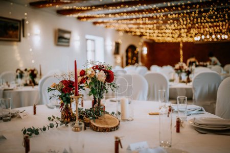Valmiera, Lettland - 19. August 2023 - Eleganter Hochzeitsempfang mit schön gedeckten Tischen mit Blumen, Kerzen und beleuchtetem Hintergrund.