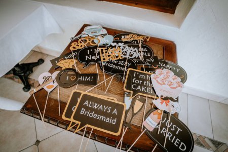 Valmiera, Latvia - August 19, 2023 - A collection of fun and quirky wedding photo booth props with humorous phrases and designs, arranged on a wooden surface.