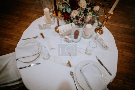 Valmiera, Latvia - August 19, 2023 - Overhead view of a wedding reception table setting with white linens, floral centerpieces, candles, and decor elements labeled "Mr" and "Mrs."
