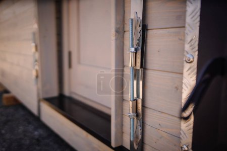 Ein Nahaufnahme-Bild, das den komplizierten Metallverriegelungsmechanismus einer Holztür zeigt, mit Schwerpunkt auf dem federbelasteten Riegel und den Schrauben.