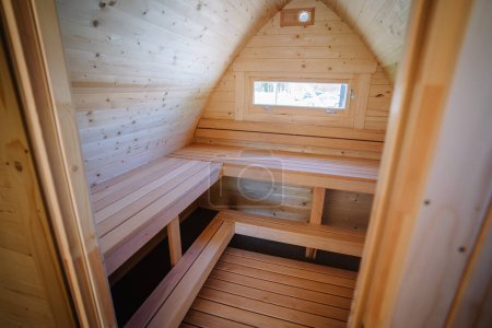 Téléchargez les photos : Vue intérieure d'un petit chalet loft avec bancs en bois et une fenêtre, toutes les surfaces recouvertes de bois de pin naturel. - en image libre de droit