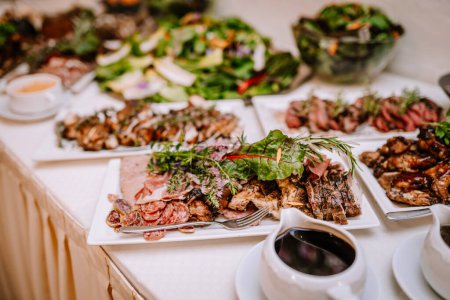 Valmiera, Lettland - 19. August 2023 - Eine Reihe von Gourmet-Gerichten auf einem Buffettisch, darunter verschiedene Fleischsorten und Salate, garniert mit Kräutern.