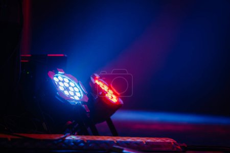 Bühnenlichter, die in dunkler Umgebung blaue und rote Strahlen abstrahlen, unterstreichen die dramatischen Effekte der Theaterbeleuchtung.