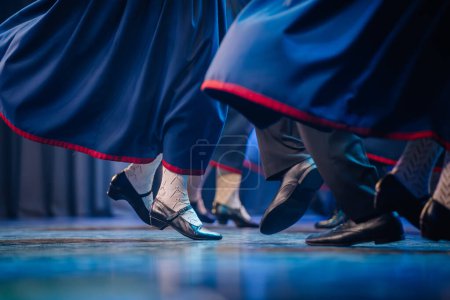 eine Nahaufnahme der Füße der Tänzer während eines lettischen Volkstanzes, bei der Bewegung und Details der traditionellen Kleidung gezeigt werden.