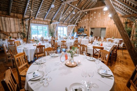 Photo for Valmiera, Latvia - August 25, 2023 - Rustic barn wedding reception setup with decorated tables and string lights. - Royalty Free Image