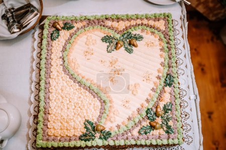 Valmiera, Lettland - 25. August 2023 - Herzförmige Hochzeitstorte mit buntem Zuckerguss und Eichenblättern mit Eicheln.
