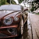 Riga, Latvia, - August 26, 2024 - Close-up of a wet brown luxury car on a city street.