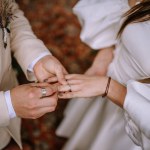 Riga, Latvia, - August 26, 2023 -  Close-up of groom placing a wedding ring on the bride's finger during their outdoor wedding ceremony.