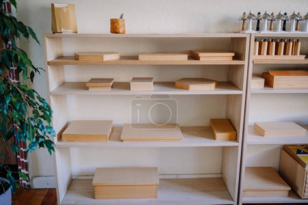 Valmiera, Latvia - May, 22, 2024 - Shelves in a Montessori classroom filled with wooden educational materials and organized tools for learning activities. A green plant is on the side.