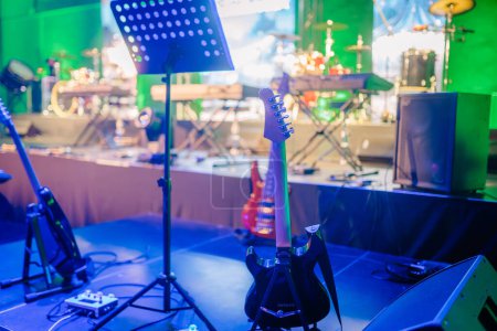 Valmiera, Lettonie - 31 mai 2024 - Guitares et matériel musical sur une scène faiblement éclairée avec un éclairage coloré, prêts pour une performance en direct, avec des instruments flous en arrière-plan.