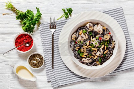 wild rice with cream, chicken, mushrooms and slivered almonds in white bowl on white wood table, horizontal view from above, flat lay, copy space