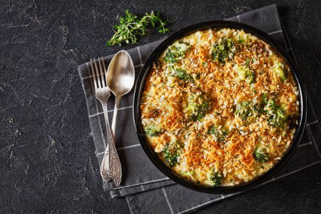 Chicken, Broccoli and mushrooms creamy Casserole topped with panko breadcrumbs in baking dish on dark concrete table, horizontal view from above, flat lay, free space