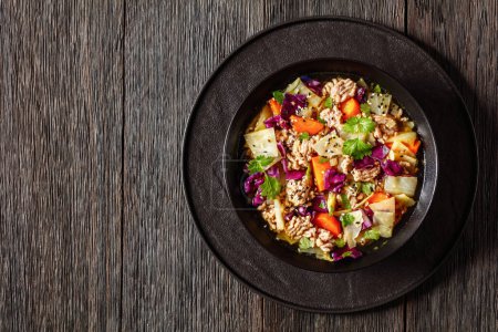 egg roll cabbage soup with ground pork and vegetables in black bowl on dark wooden table, asian cuisine, horizontal view from above, flat lay, free space