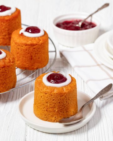 close-up of runebergin torttu, runeberg cake, a finnish mini cake flavored with almond, raspberry jam and rum on plate on white wooden table, vertical view