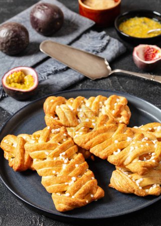 empanadas de maracuyá empanadas en plato sobre mesa de hormigón con pala de pastel, fruta fresca de la pasión, azúcar morena en el fondo, vista vertical desde arriba, primer plano