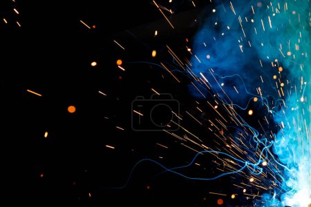 Foto de Close up view gas metal arc welding (GMAW) process with sparks, light and smoke. It is a high-speed, economical process that is sometimes referred to as metal inert gas. - Imagen libre de derechos