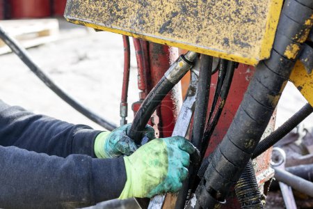 Photo for Worker is repairing hydraulic pipes of working machine. Hydraulic machines use liquid fluid power to perform work. Heavy construction vehicles are a common example. - Royalty Free Image