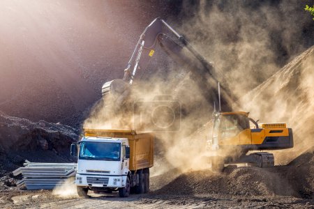 Téléchargez les photos : The excavator is digging and loading excavation to dump truck in construction field. Excavators (hydraulic) are heavy construction equipment consisting of a boom, dipper (or stick), bucket and cab. - en image libre de droit
