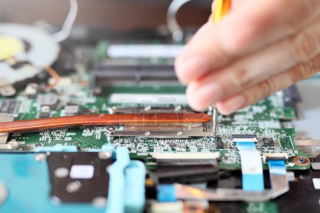 Photo for Worker is repairing to inside the laptop. The basic components of laptops function identically to their desktop counterparts. Traditionally they were miniaturized and adapted to mobile use. - Royalty Free Image