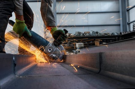 Foto de Worker is grinding and cutting to steel material with manual metal cut off wheels in the workshop. Grinding produces sparks and little fragments of metal. - Imagen libre de derechos