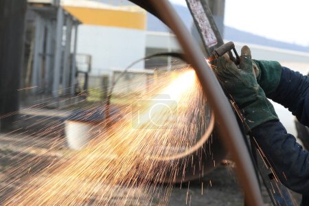 The worker is cutting to metal plate with manual flame cutting process. Oxy-fuel welding, oxyacetylene welding, oxy welding, or gas welding and oxy-fuel cutting are processes that use fuel gases.