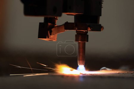 Foto de Cnc plasma cutting machine is cutting to steel plate in the factory. A Cnc plasma machine also requires a drive system, consisting of drive amplifiers, motors, encoders, and cables. - Imagen libre de derechos