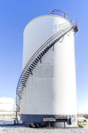 Téléchargez les photos : Vue du réservoir de stockage vertical cylindrique avec toit fixe et escalier en colimaçon dans l'usine industrielle. Réservoirs à toit fixe sont destinés aux liquides avec des points d'éclair très élevés. - en image libre de droit
