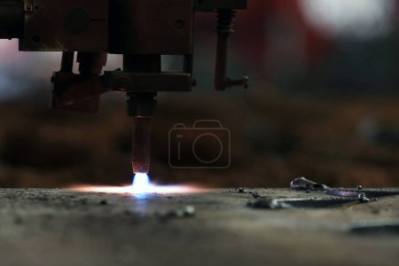 Photo for Cnc plasma cutting machine is cutting to steel plate in the factory. A Cnc plasma machine also requires a drive system, consisting of drive amplifiers, motors, encoders, and cables. - Royalty Free Image