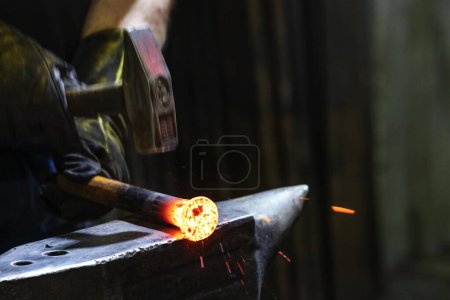 Téléchargez les photos : Vue du forgeron. Un forgeron est un forgeron qui crée des objets à partir de fer forgé ou d'acier en forgeant le métal, en utilisant des outils pour marteler, plier et couper. forgeron travaillant dans l'atelier de forgeron. - en image libre de droit