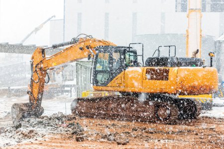 Foto de The excavator excavation at the cold weather also snowing in the construction site. - Imagen libre de derechos