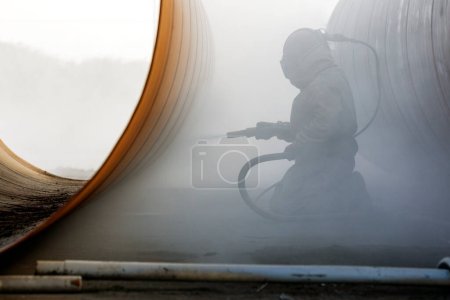 Close up view of sandblasting before coating. Abrasive blasting, more commonly known as sandblasting, is the operation of forcibly propelling a stream of abrasive material against a surface.